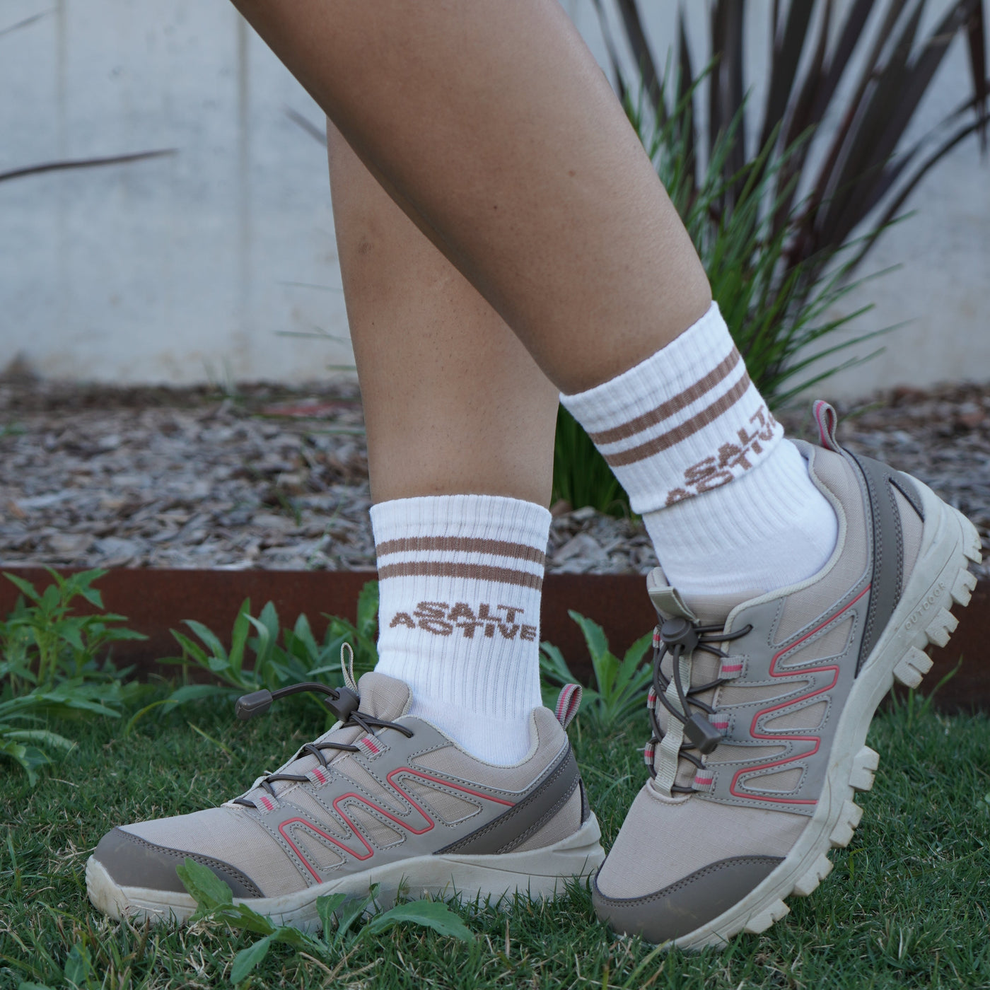 Person wearing hiking boots and white socks with red text on grass